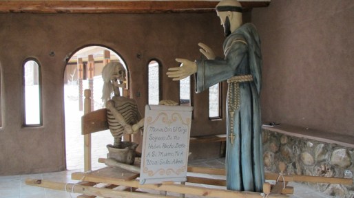 Sister Death holds a placard toward St. Francis’s outstretched arms